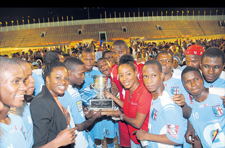 Carla Hollingworth of sponsor Gatorade (left) and Tahnida Nunes of co-sponsor Digicel (right) present the ISSA Manning Cup schoolboy trophy to St George’s College players after they defeated Hydel High 3-0 in the final at the National Stadium yesterday. (Photo: Marlon Reid)